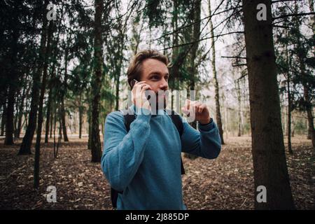 Junge erwachsene Mann am Telefon zu sprechen stehend über weiße Mauer mit Hand betonte am Kopf, mit Scham und Überraschung Gesicht schockiert, wütend und frustr Stockfoto