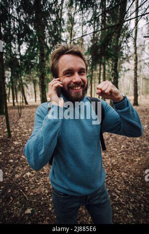 Junge erwachsene Mann am Telefon zu sprechen stehend über weiße Mauer mit Hand betonte am Kopf, mit Scham und Überraschung Gesicht schockiert, wütend und frustr Stockfoto