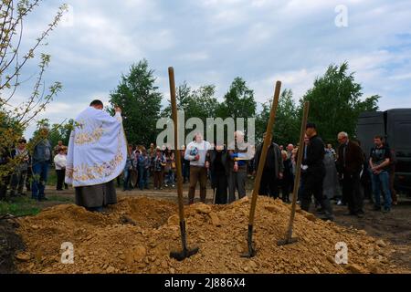 Balabyne, Ukraine. 13.. Mai 2022. Trauernde nehmen an der priestís Segnung des Sarges während der Beerdigung Teil. Russland marschierte am 24. Februar 2022 in die Ukraine ein und löste damit den größten militärischen Angriff in Europa seit dem Zweiten Weltkrieg aus (Foto von Rick Mave/SOPA Images/Sipa USA) Quelle: SIPA USA/Alamy Live News Stockfoto