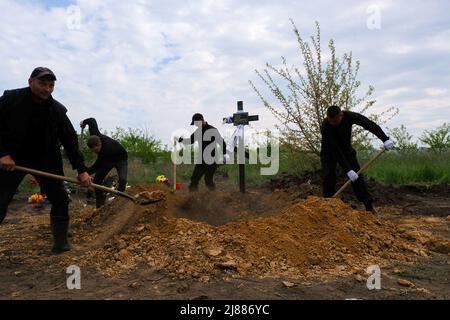 Balabyne, Ukraine. 13.. Mai 2022. Die Arbeiter der Trauerhalle bedecken den Sarg mit Erde. Russland marschierte am 24. Februar 2022 in die Ukraine ein und löste damit den größten militärischen Angriff in Europa seit dem Zweiten Weltkrieg aus (Foto von Rick Mave/SOPA Images/Sipa USA) Quelle: SIPA USA/Alamy Live News Stockfoto