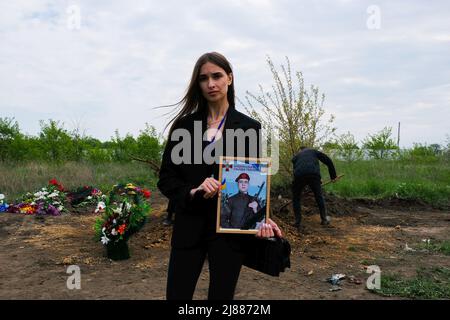 Balabyne, Ukraine. 13.. Mai 2022. Ein Cousin eines toten Soldaten zeigt sein Porträt. Russland marschierte am 24. Februar 2022 in die Ukraine ein und löste damit den größten militärischen Angriff in Europa seit dem Zweiten Weltkrieg aus (Foto von Rick Mave/SOPA Images/Sipa USA) Quelle: SIPA USA/Alamy Live News Stockfoto