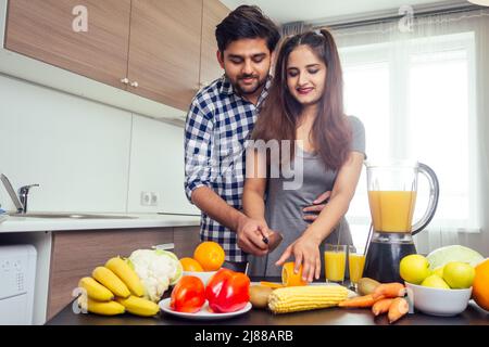 Gesunde und ökologische Lebensweise.glückliche indische Frau mit ihrem Mann, der Smoothie in der großen Küche zubereitet Stockfoto