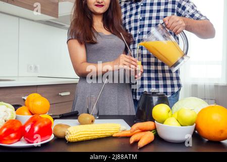 Gesunde und ökologische Lebensweise.glückliche indische Frau mit ihrem Mann, der Smoothie in der großen Küche zubereitet Stockfoto