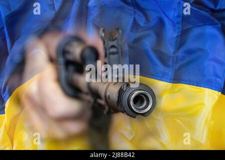 Militär ukrainischen Soldaten mit einem Maschinengewehr vor dem Hintergrund der Flagge der Ukraine, stoppen den Krieg in der Ukraine 2022 Stockfoto