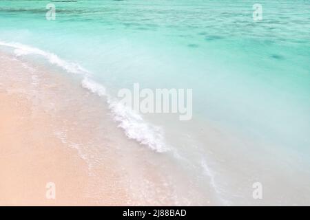 Ein Blick von einer Höhe eines tropischen Strandes und Wellen brechen auf einem tropischen goldenen Sandstrand. Die Meereswellen winden sich sanft entlang des schönen sandigen Baus Stockfoto