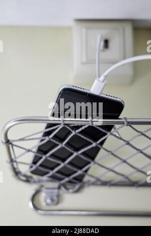 Ein Smartphone lädt in einem Abteilwagen eines Personenzuges über eine spezielle Steckdose Stockfoto