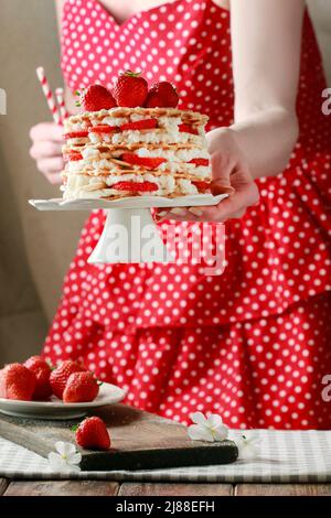Frau mit Erdbeerkuchen und Teller mit rohen Erdbeeren. Party-Dessert Stockfoto