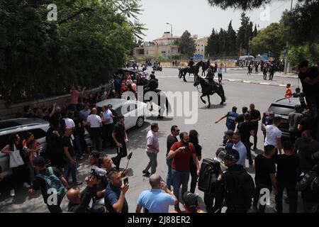 Jerusalem, Naher Osten. 13.. Mai 2022. Familienmitglieder und Freunde tragen den Sarg des Al-Jazeera-Reporters Shireen Abu Akneh, der während eines israelischen Angriffs in Jenin im besetzten Westjordanland bei Zusammenstößen mit israelischen Sicherheitskräften während der Beerdigung am 13. Mai 2022 in Jerusalem getötet wurde. Kredit: Muammar Awad/Xinhua/Alamy Live Nachrichten Stockfoto