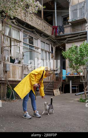 Junge Fotografin Mädchen spielt mit Katze auf der Straße in der Altstadt Stockfoto