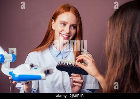 Rothaarige Ingwer junge fröhliche weibliche Klientin sitzt in der Zahnarztpraxis und bekommen Lächeln Whitening in Ei Stuhl Stockfoto