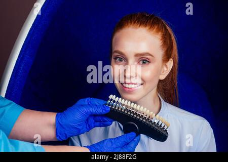 爀攀搀栀愀椀爀攀搀 最椀渀最攀爀 礀漀甀渀最 挀栀攀攀爀昀甀氀 昀攀洀愀氀攀 挀氀椀攀渀琀 猀椀琀琀椀渀最 椀渀 搀攀渀琀愀氀 漀昀昀椀挀攀 愀渀搀 最攀琀琀椀渀最 猀洀椀氀攀 眀栀椀琀攀渀椀渀最 椀渀 攀最最 挀栀愀椀爀 Stockfoto