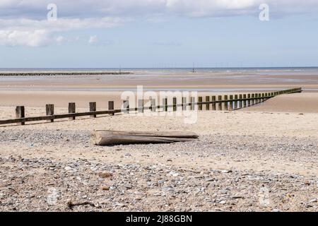 Rhyl North Wales, Blick auf das Meer, Sand und Stein, Treibholz, Rillen, die zum Meer führen, blauer Himmel mit weißen, flauschigen Wolken Stockfoto