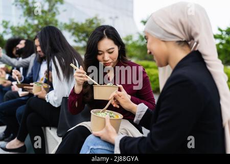 Multirassische Geschäftsleute, die eine Pause beim Essen außerhalb des Büros einlegen Stockfoto