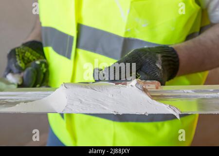 Die Hand des Meisters hält einen Spatel mit Gips, schließen. Stockfoto