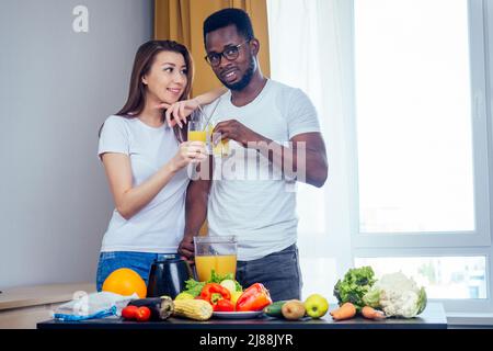 afroamerikanischer Mann mit asiatischer Frau, die zu Hause Smoothie macht Stockfoto