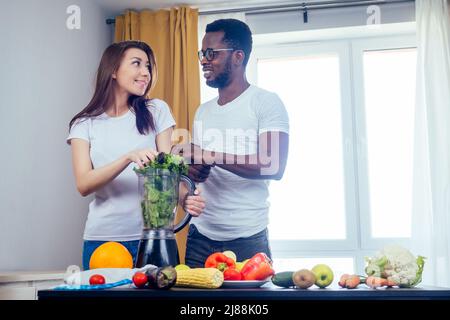 afroamerikanischer Mann mit asiatischer Frau, die zu Hause Smoothie macht Stockfoto