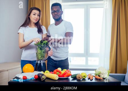 afroamerikanischer Mann mit asiatischer Frau, die zu Hause Smoothie macht Stockfoto