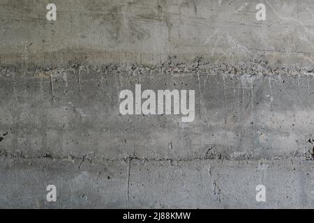 Struktur aus Stahlbeton in Schichten verlegt. Oberfläche aus altem und verschmutztem Stahlbeton mit Spuren von Schalungen. Stockfoto
