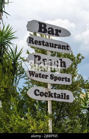 Ksamil, Albanien - 9. September 2021: Wegweiser mit Pfeil zu Bar, Restaurant, Strand, Wassersport, Cocktails. Hintergrund des Urlaubskonzepts. Stockfoto
