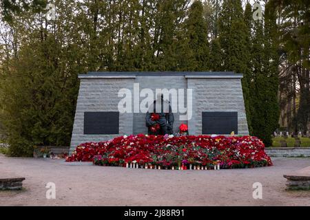 Tallinn, Estland - 12. Mai 2022: Bronze Soldat (est: Pronkssõdur) Denkmal. Veteranen der Roten Armee feiern den Victory Day mit roten Nelkenblumen Stockfoto