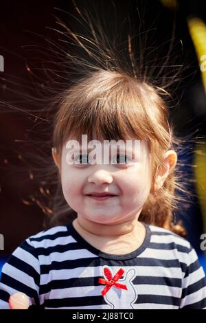 Porträt eines Mädchens mit elektrifizierten Haaren auf dunklem Hintergrund. Nettes kleines Mädchen. Nahaufnahme Porträt. Stockfoto