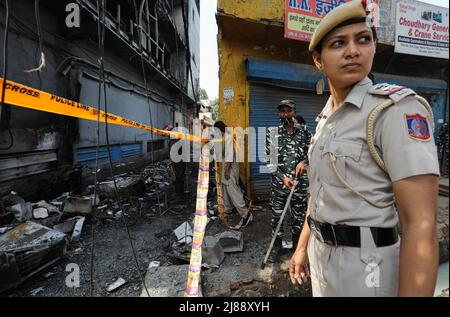 Neu-Delhi, Indien. 14.. Mai 2022. Ein Polizist aus Delhi, der einen Tag nach Ausbruch des Feuers in einem dreistöckigen Geschäftsgebäude in der Nähe der U-Bahn-Station Mundka am Freitag in der späten Nacht am Standort eines Brandes in einem Geschäftsgebäude gesehen hat. Am Delhiís Freitagabend brach ein massives Feuer auf einem Gebäude in der Nähe der U-Bahnstation Mundka im Westen aus, bei dem 27 Menschen starben und 12 verletzt wurden, teilte die Polizei mit. Kredit: SOPA Images Limited/Alamy Live Nachrichten Stockfoto