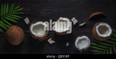Gehackte Kokosnuss auf einem hölzernen Hintergrund, Draufsicht. Kokosmilch und Kokosflocken sind tropische Lebensmittel Stockfoto