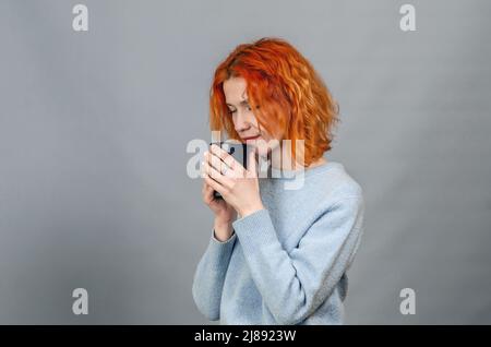 Junge rothaarige Frau mit Getränk mit geschlossenen Augen aus Lust, Seitenansicht Stockfoto