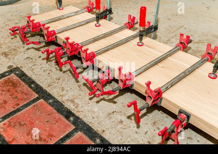 Nahaufnahme des Tischlerbefestigungsbretts mit Klammern. Schreinerei. Seitenansicht Stockfoto