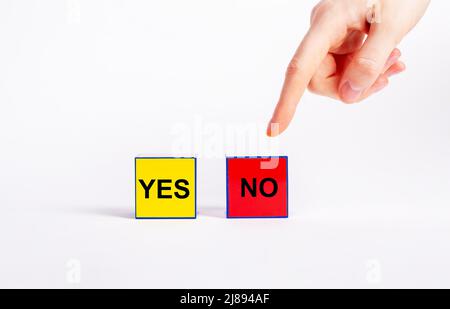 Wahl zwischen positiven und negativen Entscheidungen Konzept. Zeigefinger zeigt auf roten Würfel ohne Text anstelle von gelben mit Ja-Wort. Ablehnung, Ablehnung oder falsches Antwortkonzept. Hochwertige Fotos Stockfoto