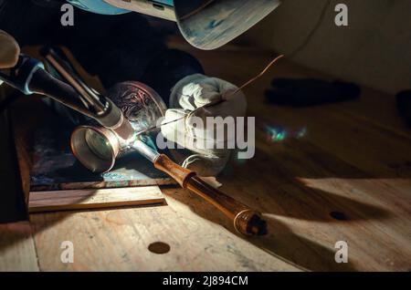 Die Hände des Schweißers in Handschuhen. Reparatur von Kaffee türk durch Schweißen. Nahaufnahme Stockfoto