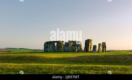 Stonehenge, prähistorische, stehende Steine, umgeben von Grasland, die in der Dämmerung in das verblassende Frühlingslicht getaucht sind. Amesbury, Wiltshire, Großbritannien. Stockfoto