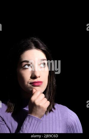 Nachdenkliche Brünette Frau mit schwarzem Hintergrund Stockfoto