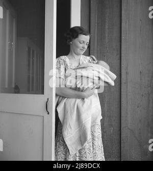 Migrantenlager der Farm Security Administration (FSA). Westley, Kalifornien. Diese Migrantenmutter lebt in einem Lager eines Auftragnehmers, weil der Auftragnehmer die Kontrolle über die Arbeitsplätze hat. Sie kommt mit der Krankenversicherungskarte (FSA) für kranke Babys und landwirtschaftliche Arbeiter zum Lager der Farm Security Administration. Stockfoto