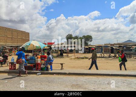 Die Menschen laufen am Marktstand vor den Geschäften und dem Marktplatz in der Stadt Kenias vorbei. Afrika Stockfoto