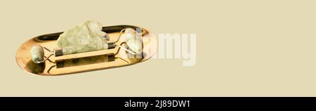 Gua Sha Massage Steininstrumente. Abstreifer und Walze auf natürlichem beigen und werdem Hintergrund. Stockfoto