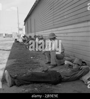 Untätige Männer saßen drei Wochen vor der Eröffnung der Kartoffelernte im Klamath Basin im Schatten auf der anderen Seite des Zeitvertreibungs-Cafés. Kalifornien, Siskiyou County, Tulelake. Stockfoto