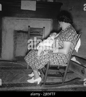 Die Frau des Pächter des Tabaks pflegt das Baby, nachdem es das Geschirr gewaschen hat und bevor es „das Haus aufrichtet“. Person County, North Carolina. Stockfoto