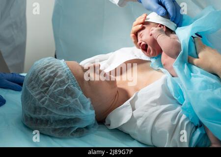 Mutter schaut auf ihr neugeborenes Baby im Krankenhaus Stockfoto