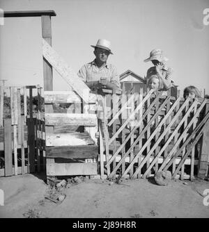 Highway City, Kalifornien, in der Nähe von Fresno. Familie aus Oklahoma; seit sechs Jahren in Kalifornien, Wanderarbeiter, die jetzt in der Works Progress Administration (WPA) arbeiten, von der sie bei der Eröffnung der Ernte 1939 abgeschnitten werden könnten. Ihr Haus stellt eine von vielen ähnlichen Strukturen dar, die sie durch ihre eigenen Bemühungen auf armes Land aufbauen wollen, für das sie ein paar Dollar pro Monat aus dem WPA-Budget bezahlen. Ihre leichte Rechnung beträgt zwei Dollar pro Monat. Wasserrechnung ein Dollar pro Monat, Kerosin für das Kochen fünf Dollar pro Monat, etwa. Sie besitzen einen 1929 Ford. „Th Stockfoto