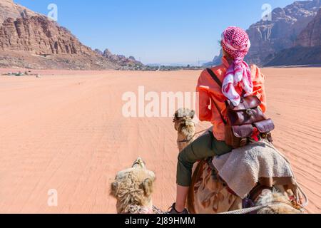 Schöne junge Frau Tourist in weißem Kleid Reiten auf Kamel in wadi Rum Wüste, Jordanien Stockfoto