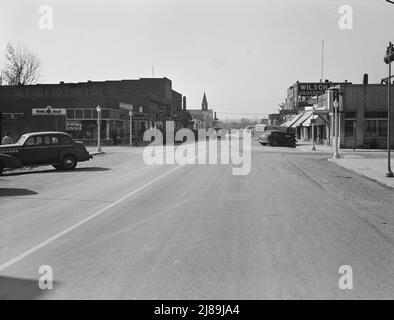 Hauptstraße von Nyssa, Oregon. Samstagnachmittag. [Schilder: 'International Harvester - McCormick-Deering Farm Machines; Dutch Boy Paints; Hardware; Lebensmittelgeschäft; Rexall Drugs; Nicht ansässige Personen melden sich hier an; Café; Dime Store; Golden Rule; Atkeson's Clothing - Women's Apparel; Rose Bud Club; Fleischwaren; Wilson Bros Groceries; Headquarters Vale-Owyhee Land Settlement Association']. Stockfoto