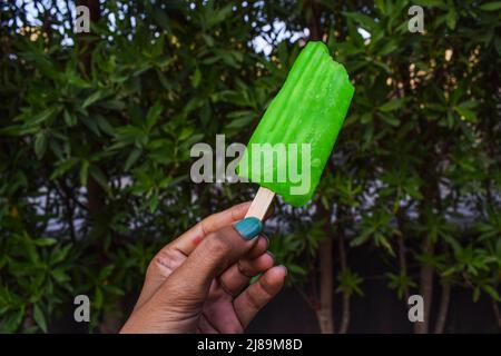 Person Essen Cold Icecream Bar Candy Frozen Dessert im rauschenden Sommer essen. Grüne Farbe Geschmack Eis Eis Eis aus rohem Mango süßen Geschmack Stockfoto