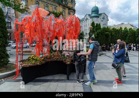 Lviv, Ukraine. 14.. Mai 2022. Die Menschen sahen sich das Kunstprojekt ''Screams of Souls'' an, das in Lemberg vorgestellt wurde. Große Karte der Ukraine mit blutigem Kinderspielzeug, zerstörten Häusern, Stacheldraht und Ähren von Weizen, die durch die verbrannte Erde sprießen. Die Autorin des Projekts ist Ulyana Datsishin. Russland marschierte am 24. Februar 2022 in die Ukraine ein und löste damit den größten militärischen Angriff in Europa seit dem Zweiten Weltkrieg aus (Bild: © Mykola Tys/SOPA Images via ZUMA Press Wire) Stockfoto