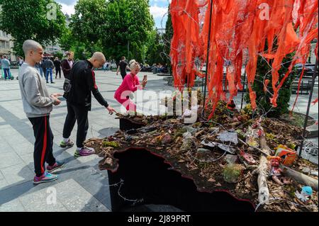 Lviv, Ukraine. 14.. Mai 2022. Die Menschen sahen sich das Kunstprojekt ''Screams of Souls'' an, das in Lemberg vorgestellt wurde. Große Karte der Ukraine mit blutigem Kinderspielzeug, zerstörten Häusern, Stacheldraht und Ähren von Weizen, die durch die verbrannte Erde sprießen. Die Autorin des Projekts ist Ulyana Datsishin. Russland marschierte am 24. Februar 2022 in die Ukraine ein und löste damit den größten militärischen Angriff in Europa seit dem Zweiten Weltkrieg aus (Bild: © Mykola Tys/SOPA Images via ZUMA Press Wire) Stockfoto