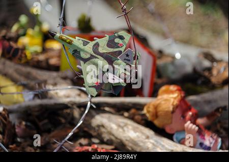 Lviv, Ukraine. 14.. Mai 2022. Spielzeug eines Flugzeugs, das beim Kunstprojekt ''Screams of Souls'' gesehen wurde, das in Lemberg vorgestellt wurde. Große Karte der Ukraine mit blutigem Kinderspielzeug, zerstörten Häusern, Stacheldraht und Ähren von Weizen, die durch die verbrannte Erde sprießen. Die Autorin des Projekts ist Ulyana Datsishin. Russland marschierte am 24. Februar 2022 in die Ukraine ein und löste damit den größten militärischen Angriff in Europa seit dem Zweiten Weltkrieg aus (Bild: © Mykola Tys/SOPA Images via ZUMA Press Wire) Stockfoto