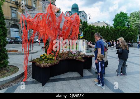 Lviv, Ukraine. 14.. Mai 2022. Die Menschen sahen sich das Kunstprojekt ''Screams of Souls'' an, das in Lemberg vorgestellt wurde. Große Karte der Ukraine mit blutigem Kinderspielzeug, zerstörten Häusern, Stacheldraht und Ähren von Weizen, die durch die verbrannte Erde sprießen. Die Autorin des Projekts ist Ulyana Datsishin. Russland marschierte am 24. Februar 2022 in die Ukraine ein und löste damit den größten militärischen Angriff in Europa seit dem Zweiten Weltkrieg aus (Bild: © Mykola Tys/SOPA Images via ZUMA Press Wire) Stockfoto