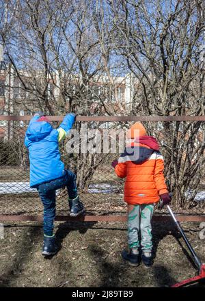 Zwei Kinder klettern über den Zaun. .Spiele für Kinder. Stockfoto