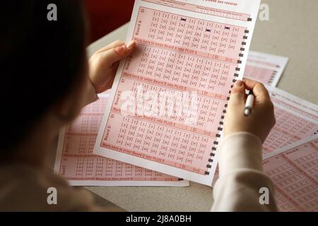 Ausfüllen eines Lottoscheines. Eine junge Frau spielt im Lotto und träumt davon, den Jackpot zu gewinnen. Spielkonzept Stockfoto