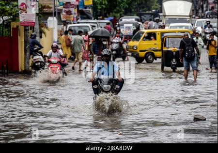 Pendler machen sich am 14. Mai 2022 in Guwahati, Indien, nach starken Regenfällen auf einer Wasserstrasse auf den Weg. Ein schlechtes Entwässerungssystem ist ein Hauptgrund für die Wasserabführung in indischen Städten. Quelle: David Talukdar/Alamy Live News Stockfoto